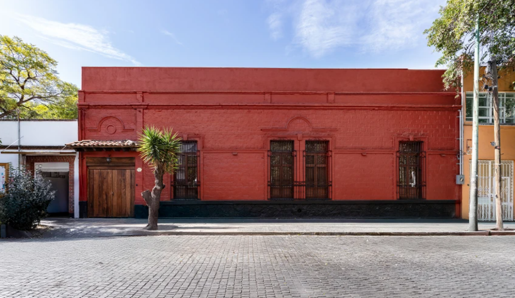 Red facade of the Casa Roja, home of the Museo Casa Kahlo, on a cobblestone street in Coyoacán