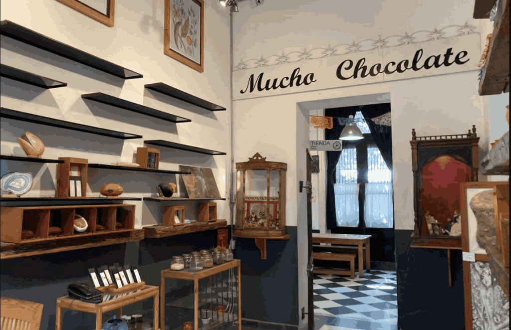Interior of MUCHO Chocolate Museum with wall shelves, glass display cases, and a checkerboard-floor room in Mexico City