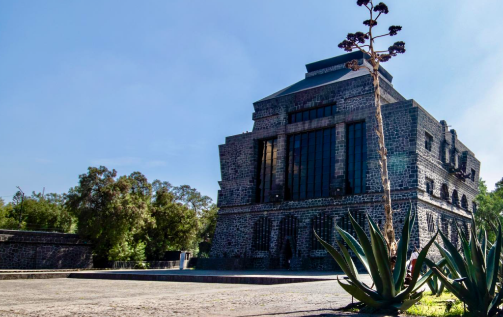 Dark volcanic stone pyramid-like facade of the Museo Diego Rivera Anahuacalli with agave plants in the foreground